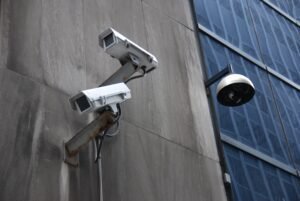 Two white security cameras mounted on a concrete building wall, emphasizing modern CCTV surveillance and Video Surveillance solutions for premises protection.