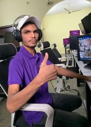 Security technician in a purple GCCTVMS uniform wearing a headset and giving a thumbs-up in a surveillance control room.
