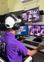 Security technician in a purple GCCTVMS uniform monitoring real-time CCTV footage on multiple screens, providing remote CCTV monitoring services.